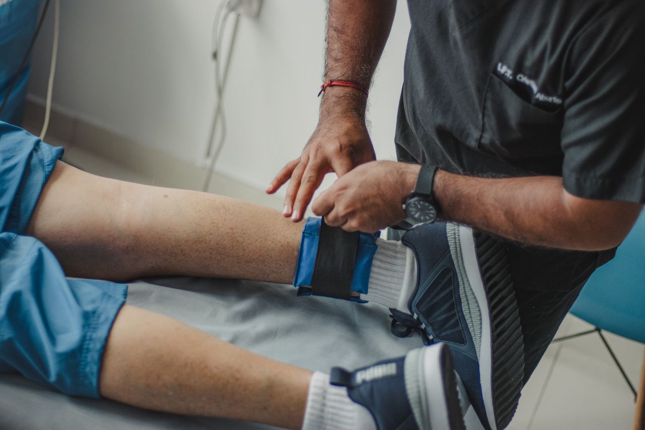 Tjänster A physiotherapist adjusts a leg strap on a patient in a clinical setting.