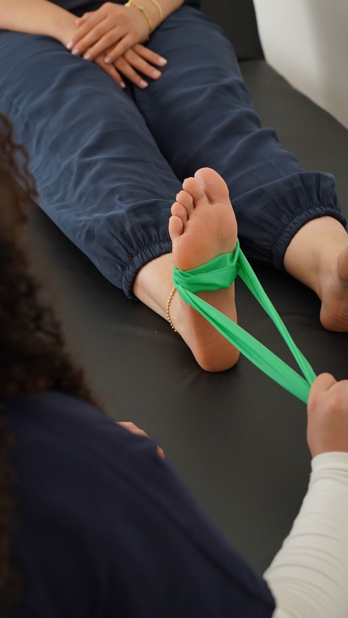 Tjänster Close-up of a physical therapy session using a resistance band for foot rehabilitation.