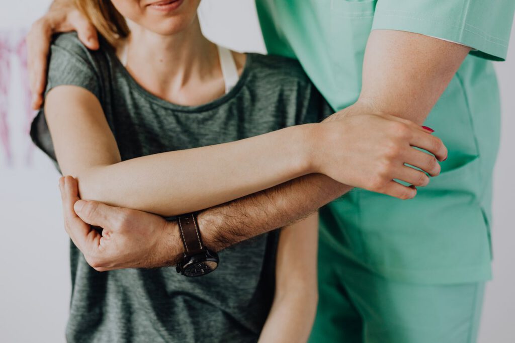 pexels photo 4506169 Crop anonymous chiropractor in uniform and wristwatch examining shoulder of smiling faceless woman in casual clothes in doctor office in clinic